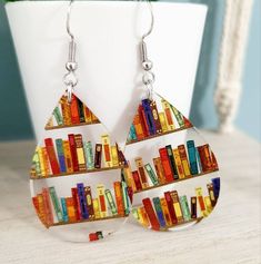 Lightweight and colorful, these teardrop earrings are on clear acrylic and feature book shelves. All findings are stainless steel and include rubber backings to keep secure.  Nickel-free and lead-free.  Perfect gift for the book enthusiast, teacher, professor, writer, bookworm, or librarian. Unique Christmas and school gift!  Reading and English teachers adore these! Ready to ship! Drop length is 2.25 inches. Please see photo for size reference.  🤍 Please note that pattern placement will vary s Cheap Artistic Earrings As Gift, Best Guy Teacher Christmas Gifts, Unique Professor Gifts, Book Earrings, Book Enthusiast, Modern Earrings, Mini Books, Librarian, Teardrop Earrings