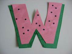 the letter w is made out of paper with black dots on pink and green strips