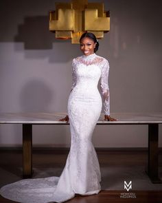 a woman standing in front of a table wearing a white dress