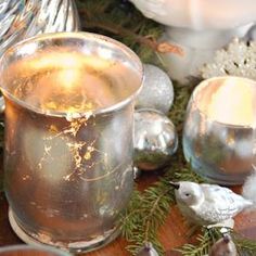 two silver cups sitting on top of a wooden table next to christmas decorations and candles