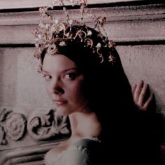 a woman wearing a tiara standing next to a wall