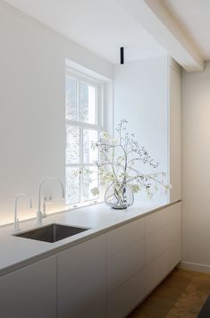 a white kitchen with a sink and window