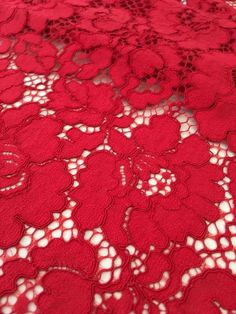 red lace with flowers on it is laying on the tablecloth, ready to be sewn