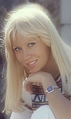 a woman with blonde hair and a watch on her wrist is posing for a photo