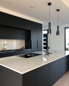 a modern kitchen with black cabinets and white countertops is seen in this image from the front view