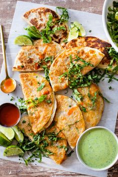 several quesadillas on a white plate with salsa and avocado