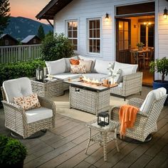 an outdoor living area with wicker furniture and lights on the patio at night time