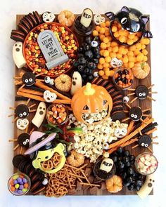 a wooden tray filled with lots of halloween food and decorations on top of each other