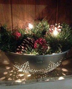 a metal bowl filled with pine cones and lights