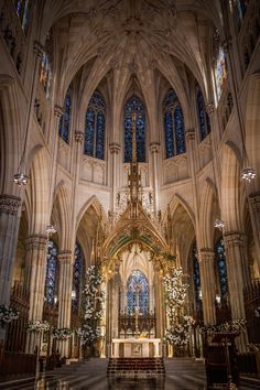 the interior of a cathedral with high ceilings and stained glass windows, decorated for christmas