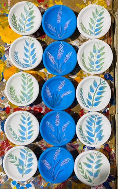 several plates with painted leaves on them in a box