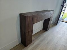 a wooden bench sitting on top of a hard wood floor next to a white wall