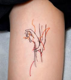 a woman's arm with an orange and black line work tattoo on her left thigh