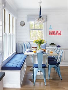 the dining room table has blue chairs and is next to a breakfast nook with built - in benches