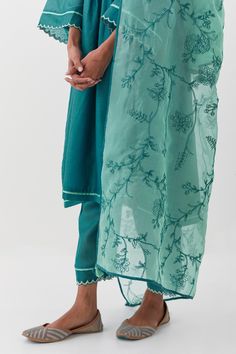 Teal blue kurta featuring pintucked bodice highlighted by scalloped hem. Comes with a pant and embroidered dupatta.
Components: 3
Pattern: Embroidered
Type Of Work: Jaali
Neckline: V-neck
Sleeve Type: Full
Fabric: Chanderi Silk, Silk Organza
Color: Blue
Other Details: 
Attached lining
Resham embroidered dupatta
Cut-work hem
Occasion: Mehendi and Haldi - Aza Fashions Elegant Turquoise Set With Dupatta, Turquoise Chanderi Sets, Turquoise Salwar Kameez With Dupatta, Turquoise Cutdana Sets, Blue Chanderi Salwar Kameez For Summer, Blue Chikankari Embroidery Salwar Kameez, Cotton Silk Self Design Dupatta, Blue Fitted Cotton Silk Salwar Kameez, Blue Kurta