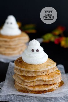 a stack of pancakes topped with whipped cream and ghost faces on top of each other