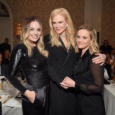 three women standing next to each other in front of a table