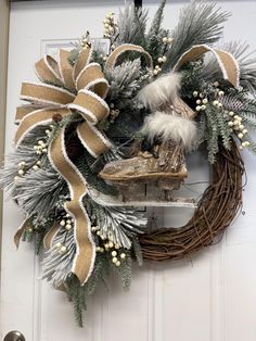 a wreath hanging on the front door decorated with pine cones, feathers and white berries