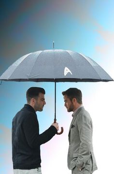 two men are standing under an umbrella and one is holding the other's hand