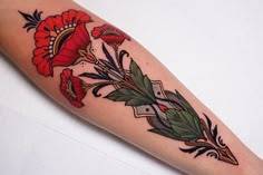 a woman's arm with red flowers and green leaves on the left side of her body