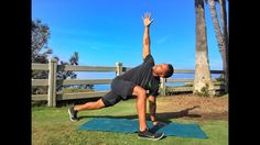 a man doing a yoga pose on a blue mat in the grass with palm trees behind him