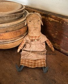 an old doll sitting next to stacked wooden plates