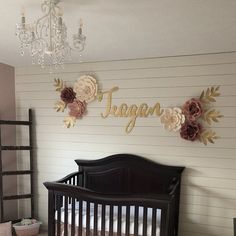 a baby's room decorated in pink, white and gold with flowers on the wall