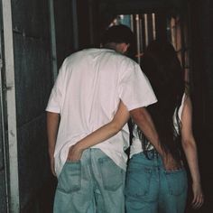 a man and woman walking down an alley way with their back to the camera, looking at each other