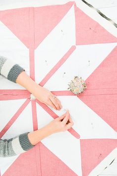 two hands on top of a pink and white quilt