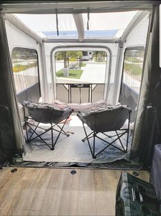 two chairs sitting in the back of a camper with doors open to let people inside