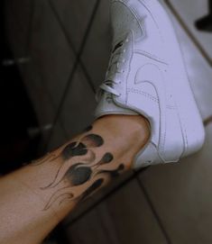 a person with a tattoo on their arm holding a tennis shoe in his left hand