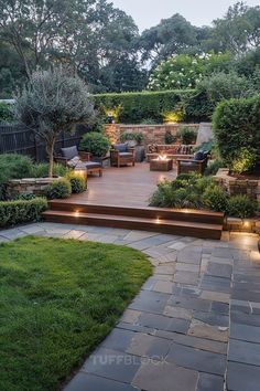 an outdoor patio with steps, seating and landscaping lights in the evening light up the landscape