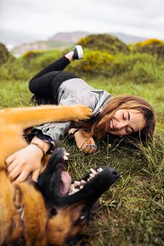 a woman laying on the ground next to a dog with it's mouth open