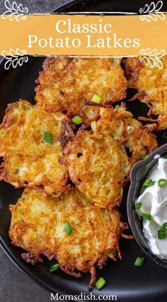 potato latkes with sour cream and chives on a black plate next to a bowl of sour cream