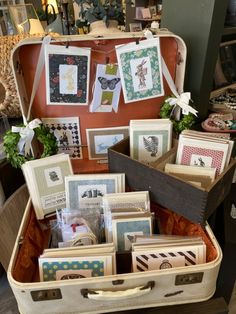 an open suitcase filled with lots of cards and pictures next to a basket full of other items