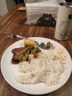 a white plate topped with rice, meat and veggies next to a cup