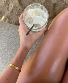 a woman is sitting on the floor with her legs crossed and holding a drink in front of her