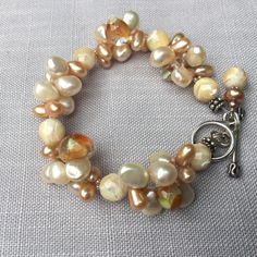 "Cream colored mixed drop pearls. Lampwork glass drops clustered braclet. 8mm faceted cream mother-of-pearl round beads. Tiny seed pearls.  7 and 1/2 \" long. Can be extended 1/2 \" upon request to seller by message seller. Sterling silver Toggle and findings." Handmade Cream Pearl Bracelet With Round Beads, Cream Pearl Bracelet With Round Beads, Cream-colored Round Pearl Bracelet, Cream Beaded Pearl Bracelet, Handmade Cream Pearl Beaded Bracelets, Cream Pearl Beaded Bracelets With Round Beads, Cream Pearl Beaded Bracelet With Round Beads, Adjustable Cream Pearl Bracelet, Cream Jewelry With Pearl Charm And Round Beads