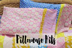 a bed with pink and yellow pillows on it next to a wicker headboard