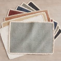 a pile of different colored rugs sitting on top of a wooden floor