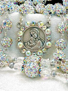 Stunning and full of fire, this is a full five decade rosary that has a lot of Aurora Borealis shimmer yet is lightweight. All prayers are said on the 8mm pave rhinestone beads, dressed with Preciosa beautiful Aurora Borealis faceted crystals. This rosary is a show stopper to be sure! The beautiful oxidized silver centerpiece is the Madonna and Child in the middle, and the crucifix is also oxidized silver with crystallized ornate detail. Perfectly beautiful! Every order comes with a lovely rosar Spiritual Beaded Rosary Bracelet For Wedding, Handmade Silver Rosary Bracelet For Wedding, Luxury Beaded Rosary As Gift, Handmade Silver Wedding Rosary, Silver Rosary For Baptism, Silver Spiritual Wedding Rosary, Luxury Handmade Spiritual Rosary, Silver Beaded Spiritual Rosary, Silver Hand-strung Rosary As Gift