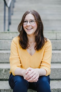 a woman with glasses sitting on some steps