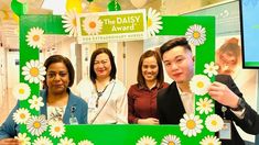 four people standing in front of a daisy frame