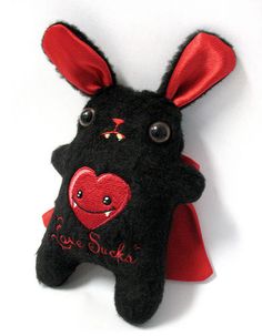 a black stuffed animal with a red heart on it's chest