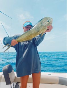 a man holding a large fish while standing on a boat