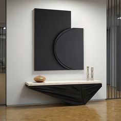 a black and white art piece sitting on top of a wooden shelf next to a wall