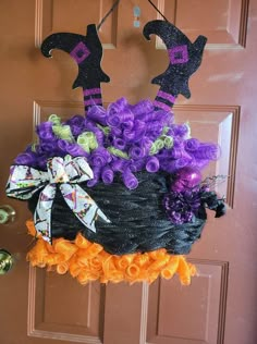 a door hanger decorated with purple and orange flowers, witch hats and brooms