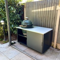 an outdoor bbq grill in front of a wooden fence with a lamp next to it