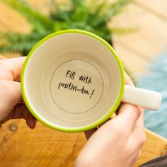 a person holding a green and white coffee cup with the words fill with positive - tea on it