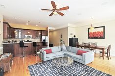 a living room filled with furniture next to a kitchen and dining room table on top of a hard wood floor